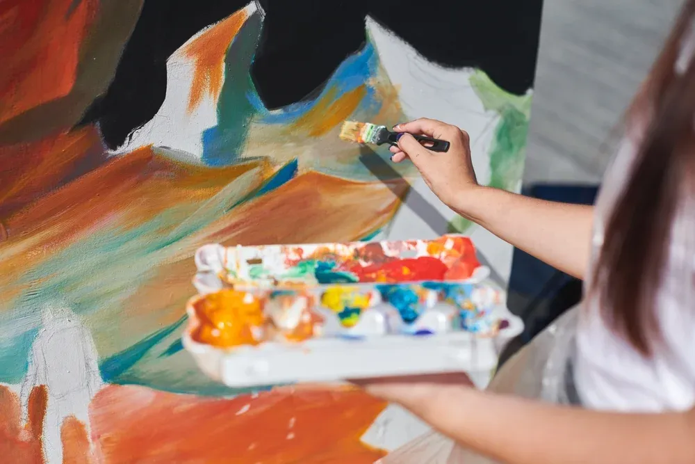 Participante peignant une fresque collective lors d'un atelier créatif